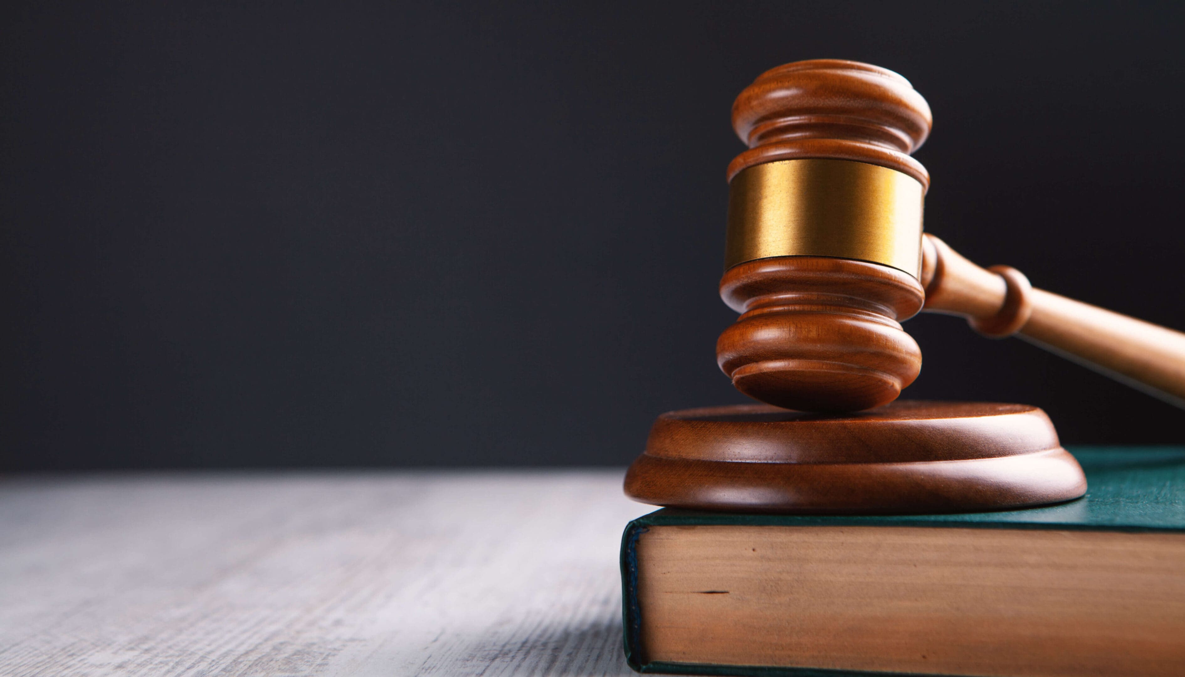 A wooden judge 's gavel on top of an open book.