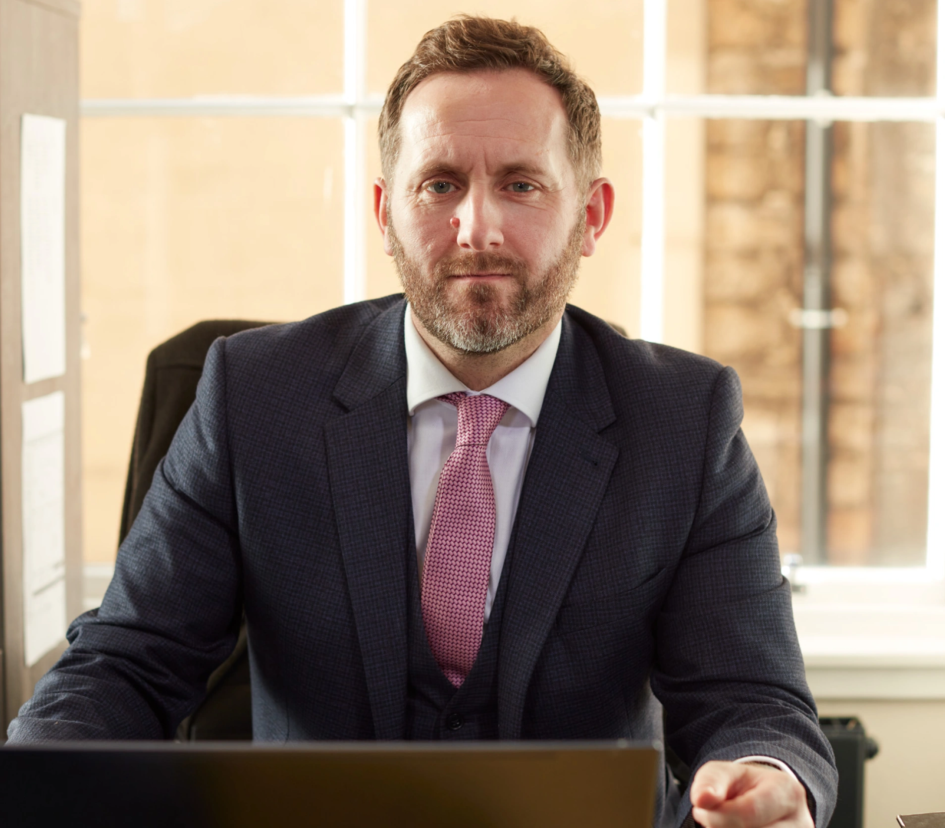 A man in suit and tie sitting at a desk.