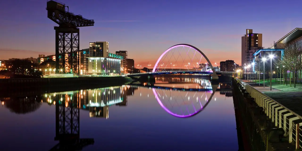 A city skyline with buildings and water at night.