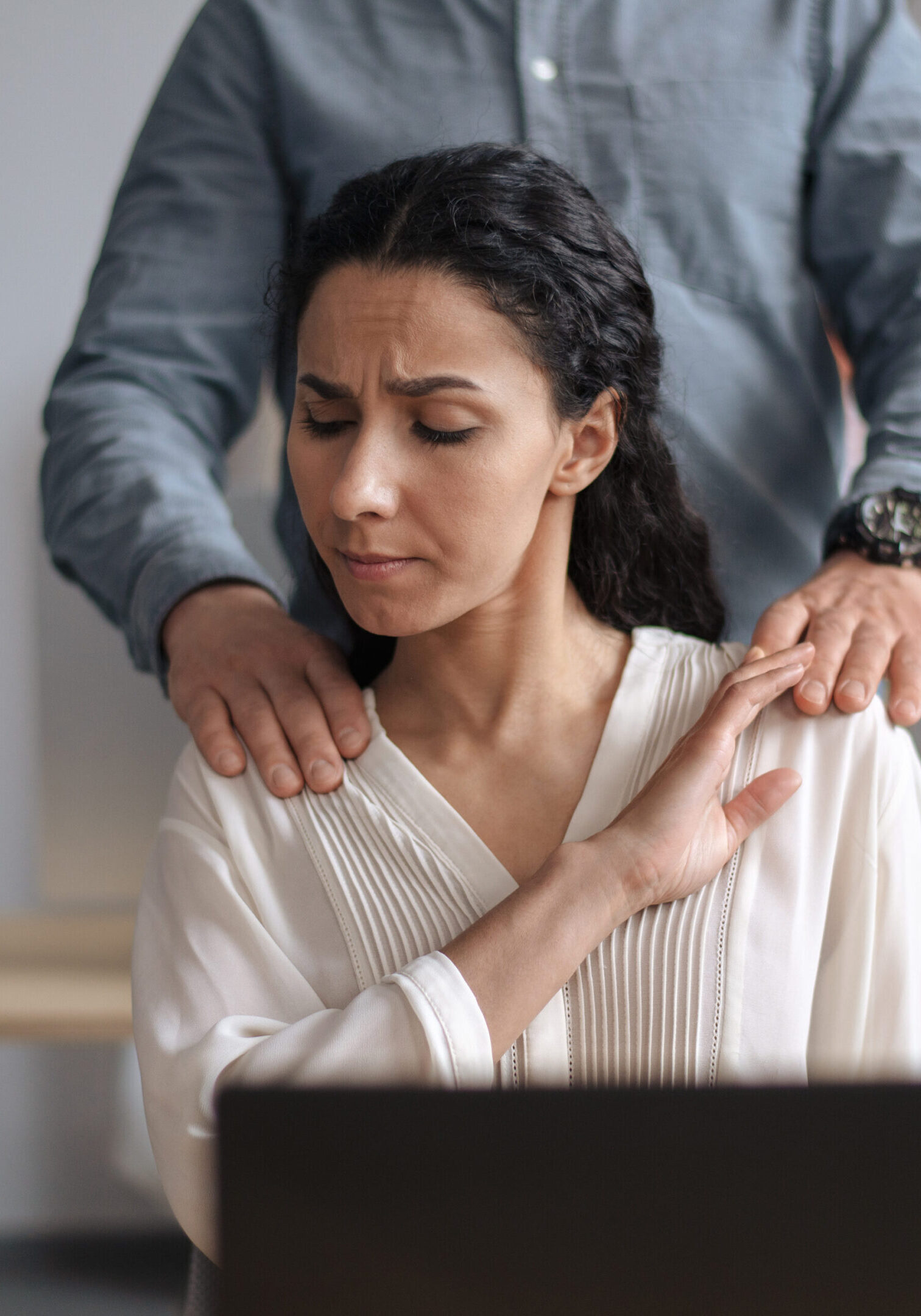 Say no to harassment. Male boss putting his hands on female secretary's shoulders, young woman feeling disgusted over molesting at company office. Sexual abuse at workplace concept